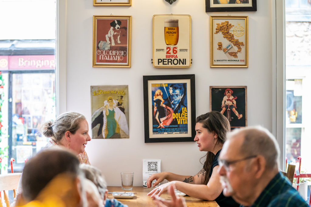 People sat in a restaurant with Italian signage on the wall.